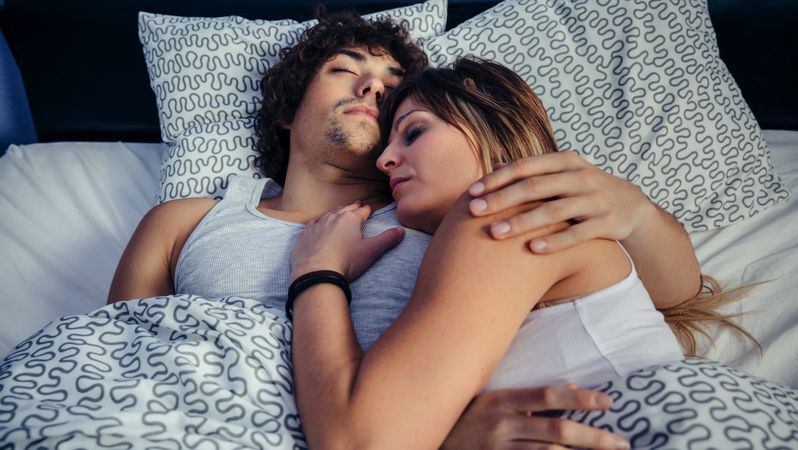 Woman resting on man's chest in bed