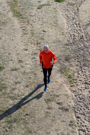 Looking down at man running on sandy terrain