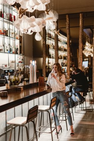 Stylish woman drinking wine in bar