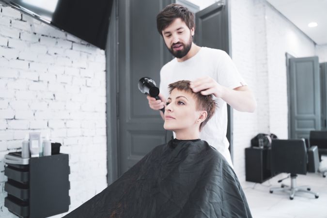 Hairdresser drying hair to woman