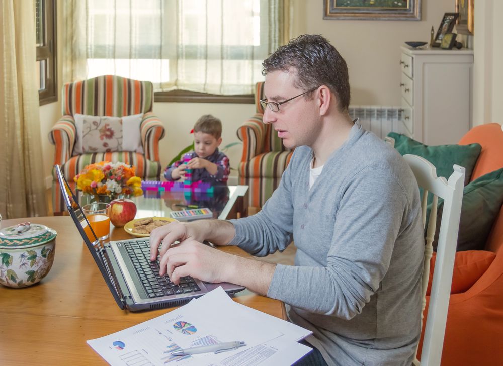 Father working in home office and son playing