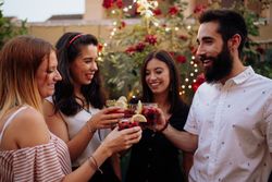 Group of cheerful friends clinking glasses at party