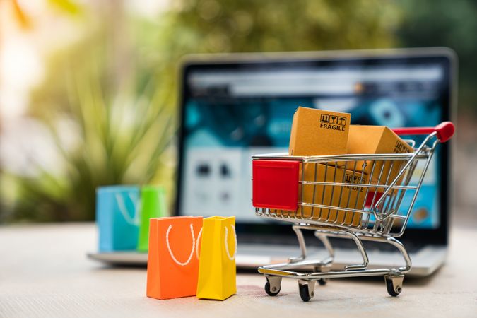 Shopping Cart with Parcels and Bags in Front of Laptop Screen