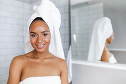 Fresh faced Black woman in towels after a shower in bright bathroom
