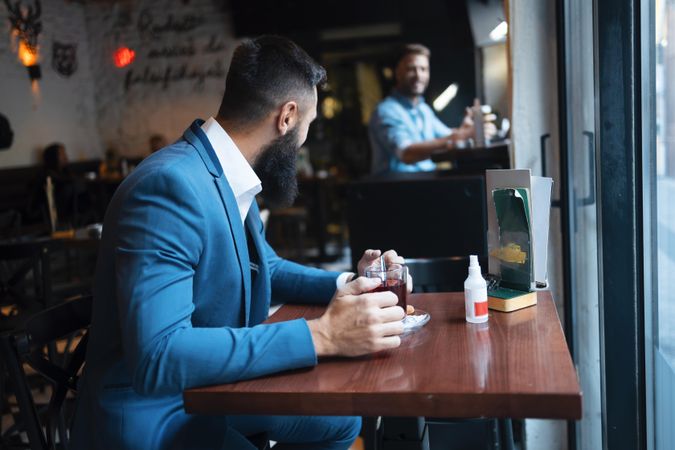 Man with tea talking to someone behind him