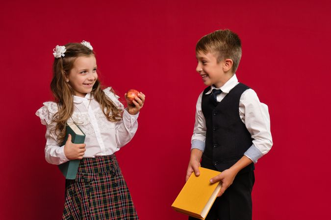 Happy preteen schoolchildren in uniform with books and apple
