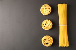 Flat lay composition with pasta on dark background, space for text