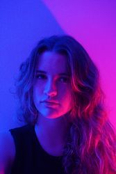 Portrait of teenage girl with long hair in purple lit studio