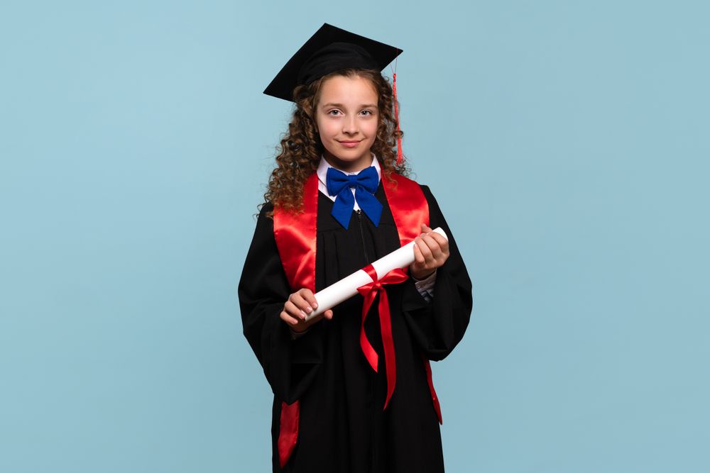 Young girl in graduation attire holding diploma