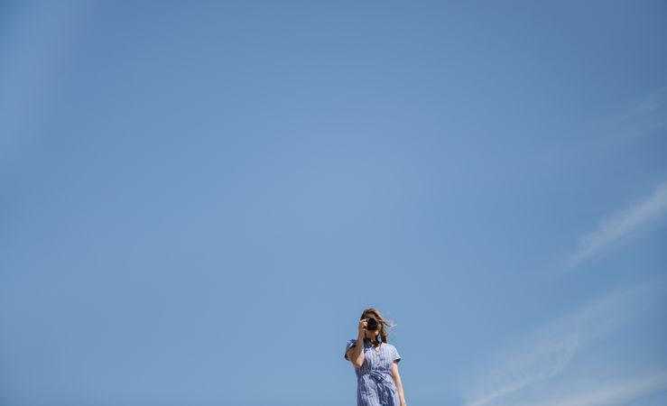 Traveling young female taking photo against blue sky