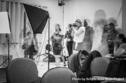 Grayscale photo of a photographer shooting in a room filled with people 0JJgN0