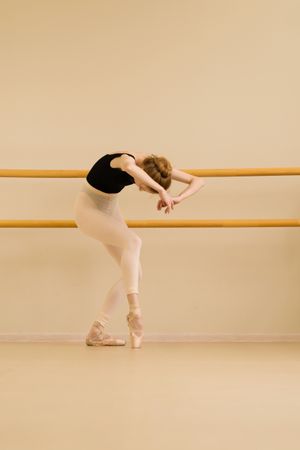 Ballet dancer stretching, leaning forward with curved posture.