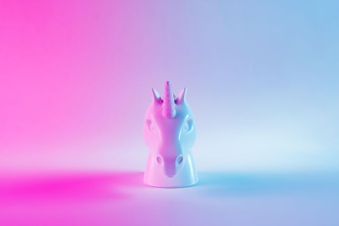 Painted unicorn head in bold pink and blue neon colors on gradient background