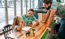 Parents drawing with their daughter while working in a coffee shop