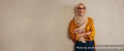 Portrait of a happy muslim woman standing against a wall 5poR80