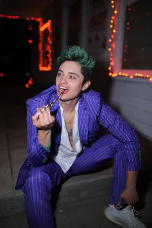 Man in blue suit with green dyed hair sitting on stair step at night