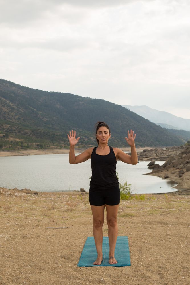 Woman practicing yoga outdoors near water