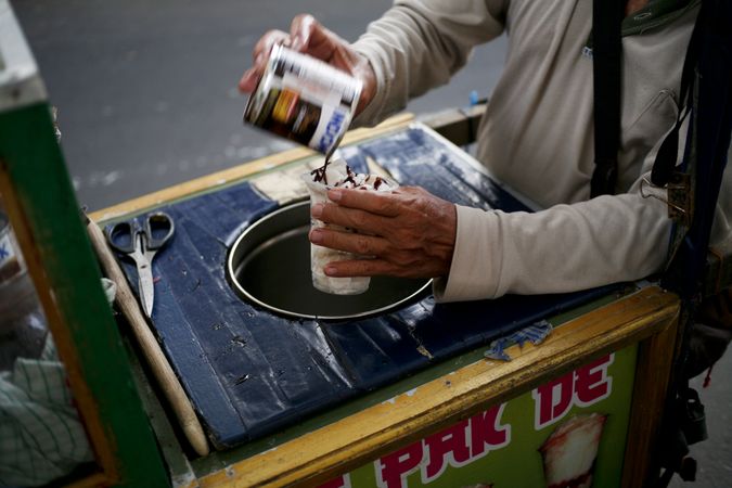 Street vendor putting chocolate sauce on ice cream
