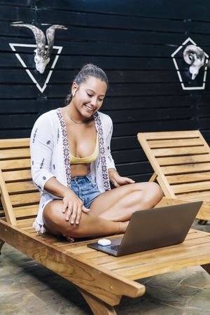 Relaxed woman using laptop while resting on deck chair