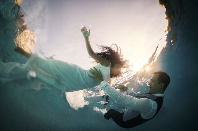 Bride and groom swimming underwater