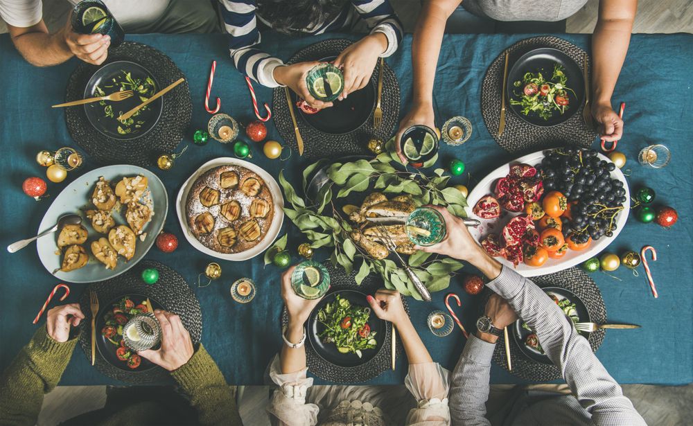 Group holding cocktails over table at festive table with candy canes and roasted pears