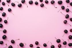 Many cherries scattered over a pink background blank space in the center