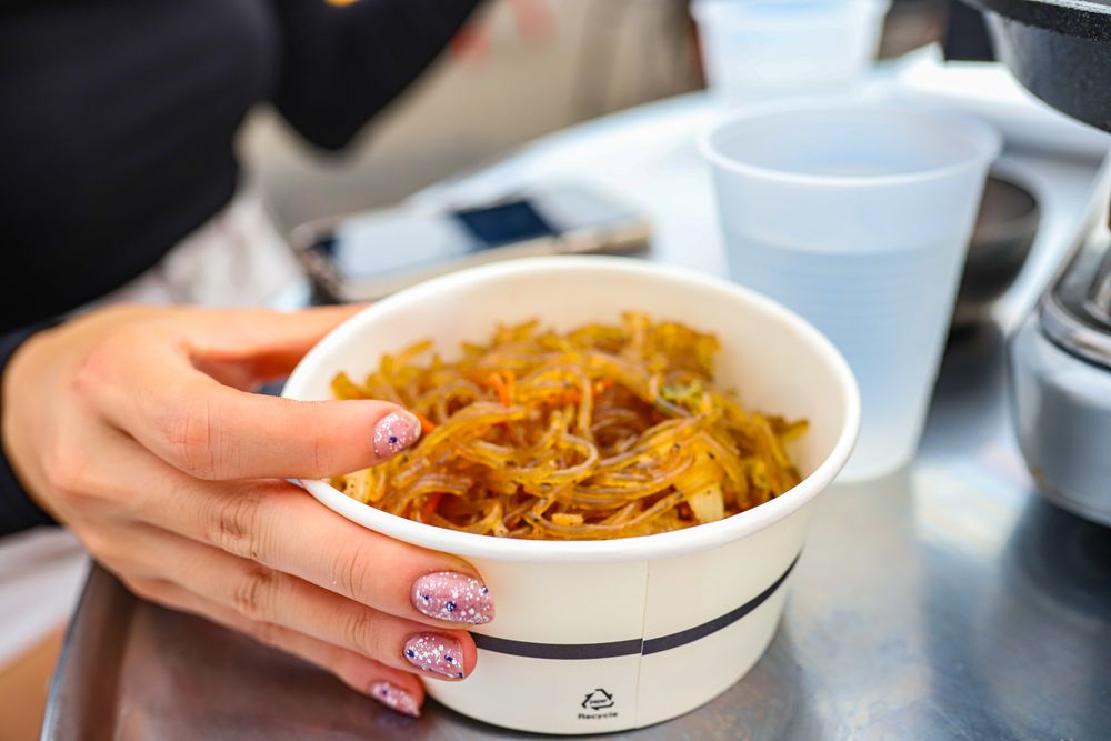 Woman holding plastic cup of pasta