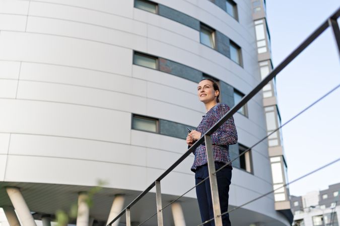 Serious businesswoman leaning on railing