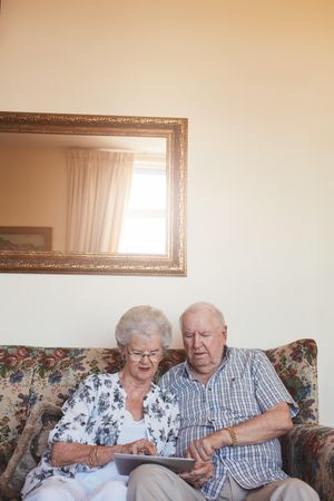 Vertical indoor shot of couple at home using digital tablet