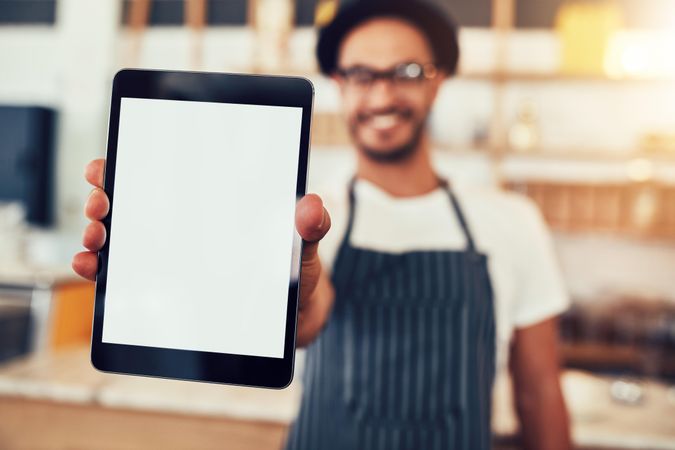 Close up portrait of a waiter holding up a tablet computer with a empty display