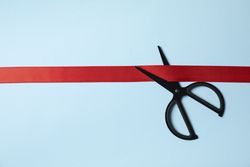 scissors and red ribbon on blue background