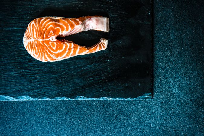Looking down at salmon steak on dark counter with space for text