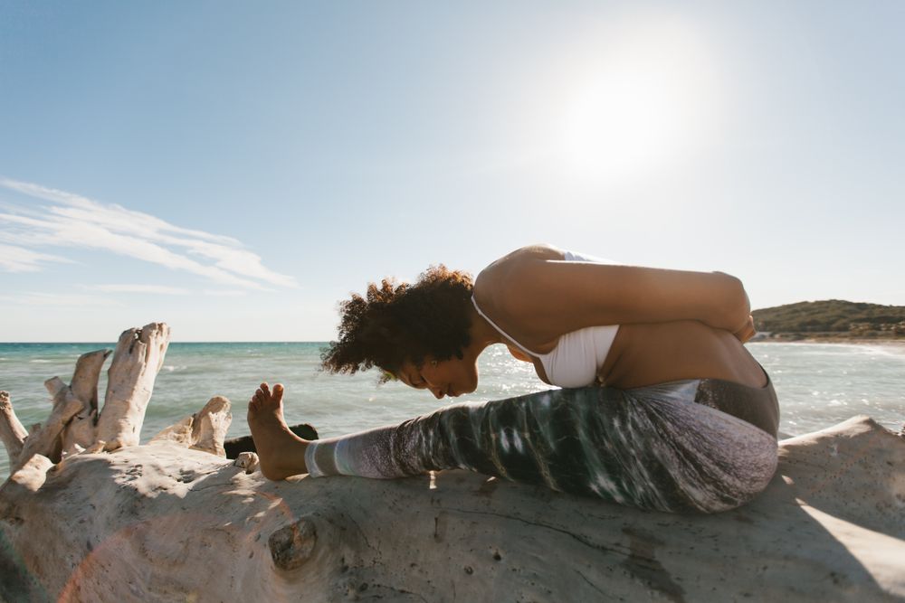 Sportive woman performing yoga posture on stones in nature