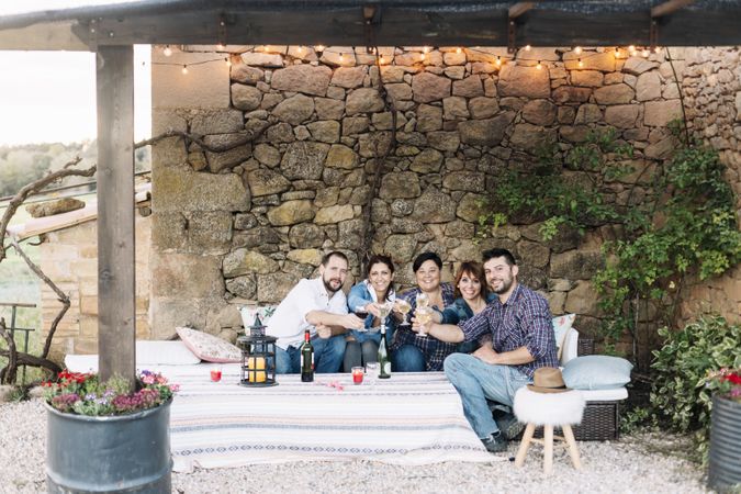 Portrait of happy group of friends sitting together and laughing while enjoying wine at a party