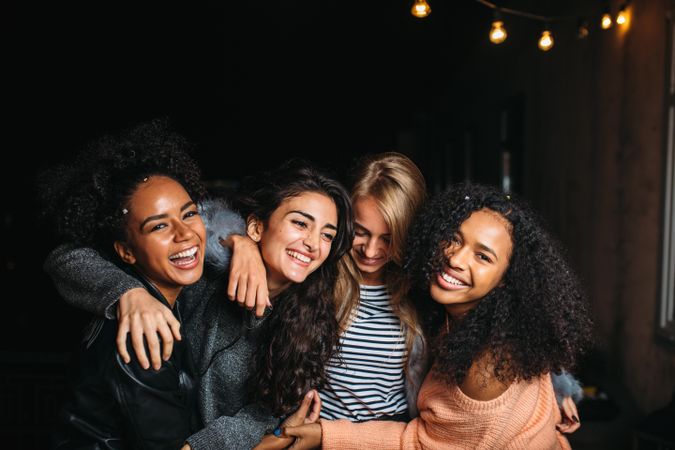 Multi-ethnic group of smiling women embracing outside