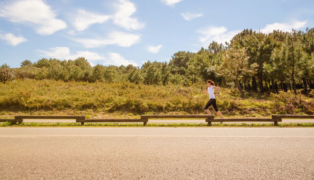 Side view of woman in athletic gear jogging along road