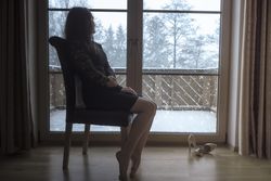 Woman sits on a chair in front of glass doors