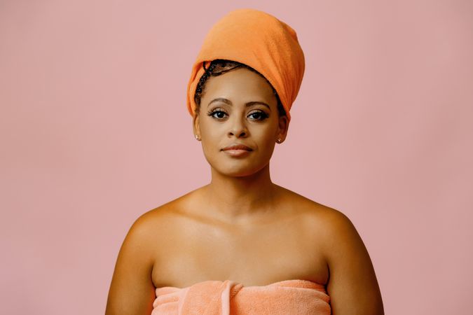 Serious female in towel with her hair wrapped after shower