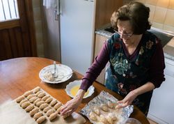 Older woman preparing lots of handmade croquettes at home