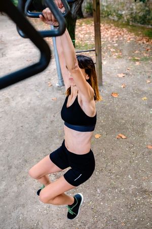 Unrecognizable woman doing monkey exercises on rings