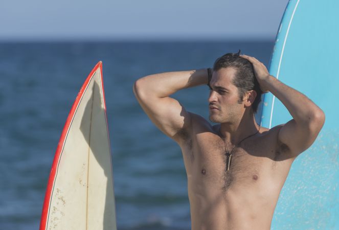 Male surfer standing with boards in front of the sea