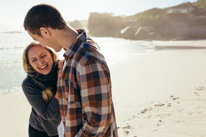 Young woman laughing with her boyfriend at the beach
