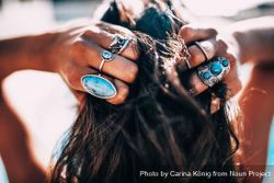 Woman wearing turquoise rings holding her hair y0vRo0