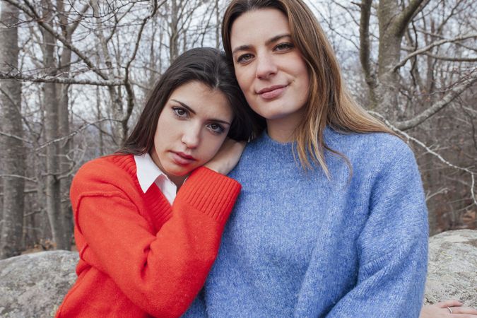 Smiling women in sweaters hugging in park