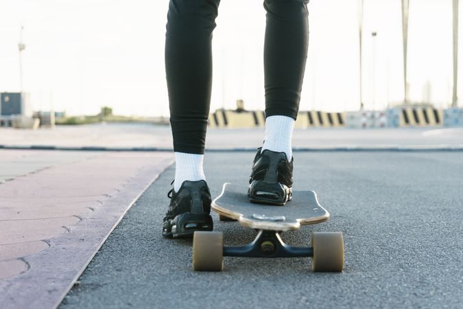 Feet of woman on longboard on street