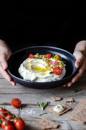 Crackers and herbs near plate with labneh