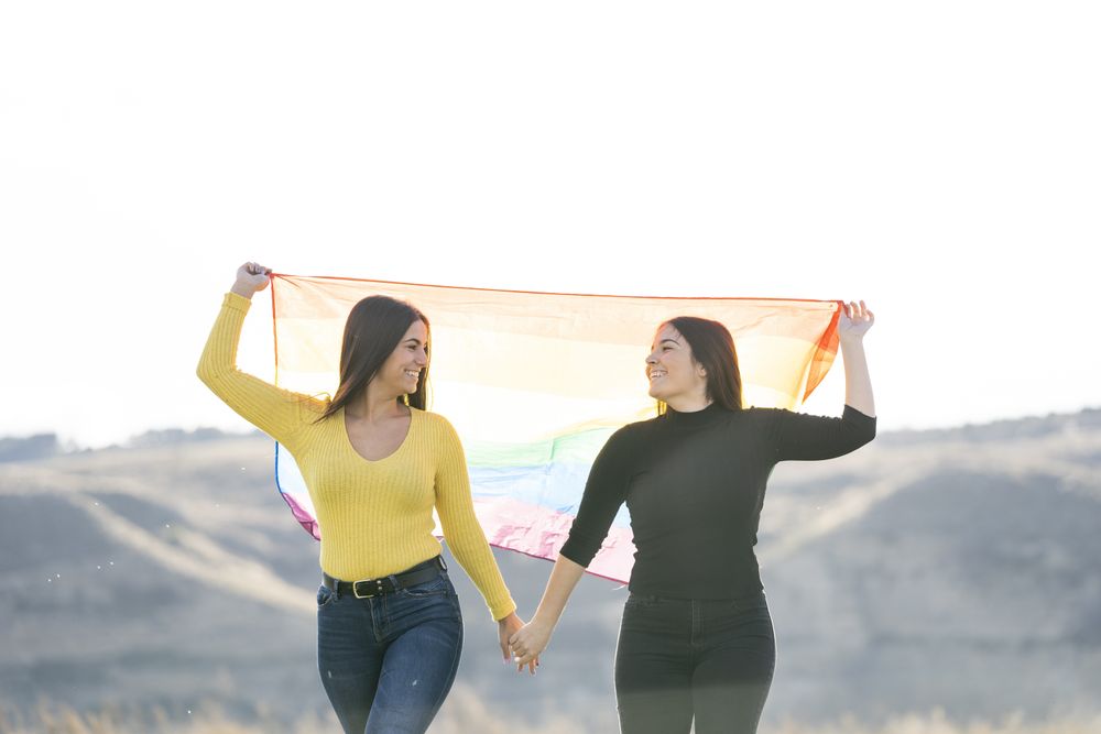 Young female couple with gay flag