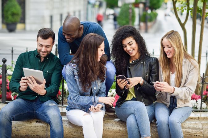 Women and men smiling and laughing in the street wearing casual clothes