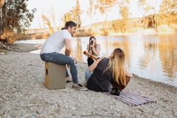 Young woman shooting friend playing guitar