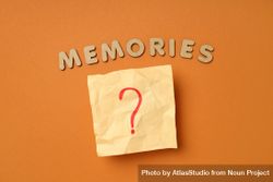 The word “Memories” written in cork on dusty orange background with post it note 5zqXN0